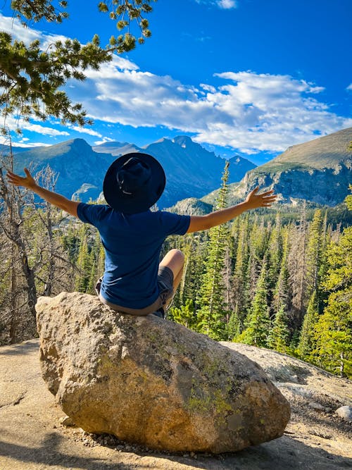 Person Sitting on Rock on Mountain Top Overlooking Valley