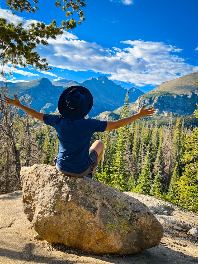 Person Sitting On Rock On Mountain Top Overlooking Valley