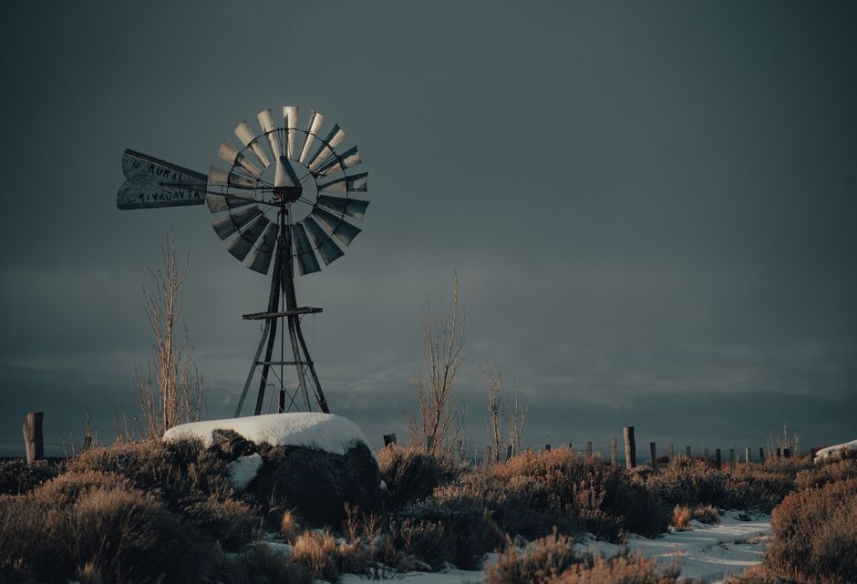 A scenic winter landscape featuring a rustic windmill surrounded by snow and a serene countryside atmosphere.