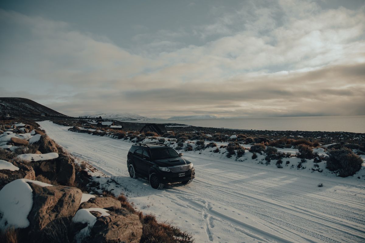 Black SUV driving along a snow-covered road in winter