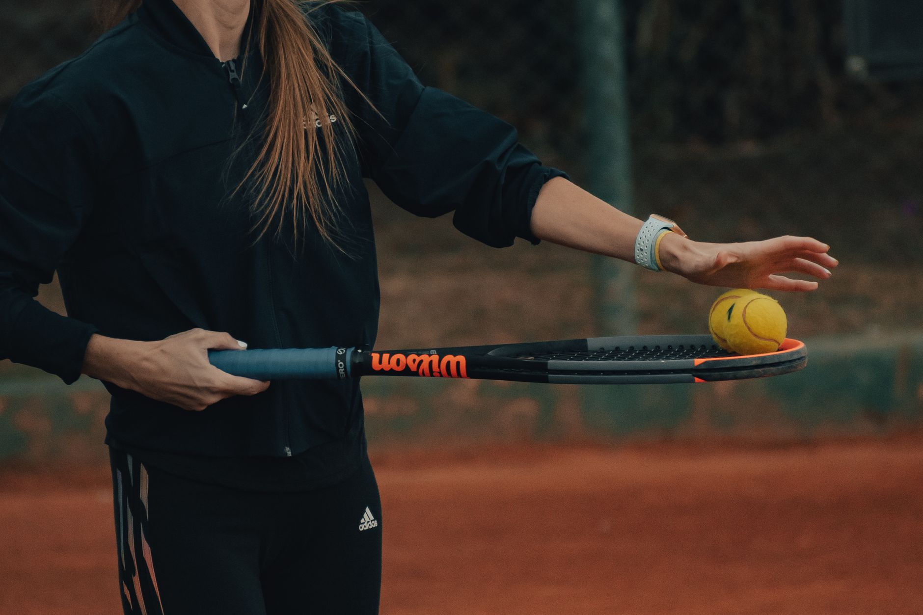 Female tennis player practicing her shot on a clay court.