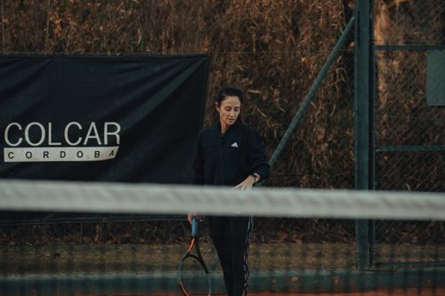 Free A woman holding a tennis racket on an outdoor clay tennis court next to a COLCAR CORDOBA sign. Stock Photo