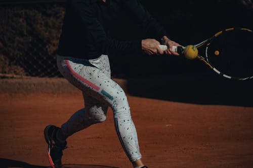 Free A Person in Black Jacket and White Leggings Playing Tennis Stock Photo