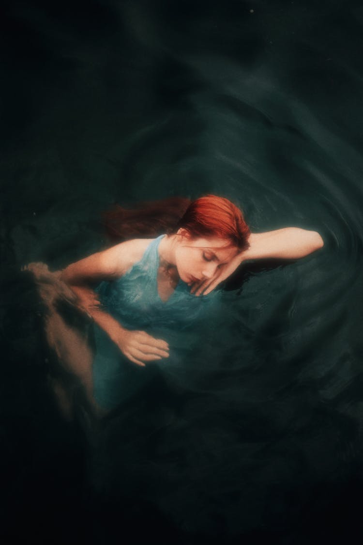 Redhead Woman Floating On The Water Surface 