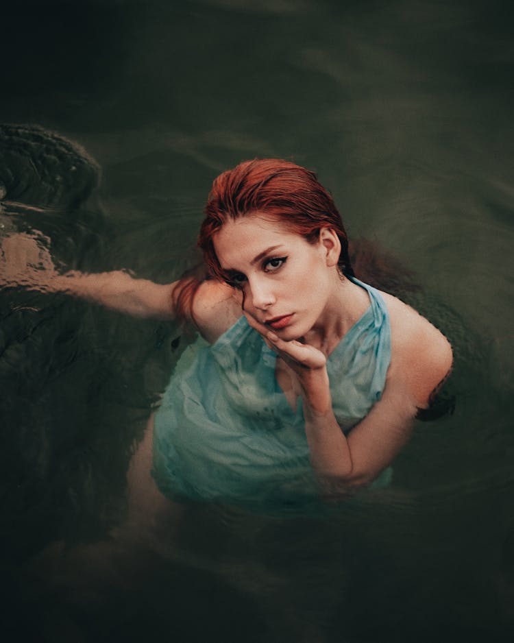 Redhead Woman Floating In Water And Looking Up 