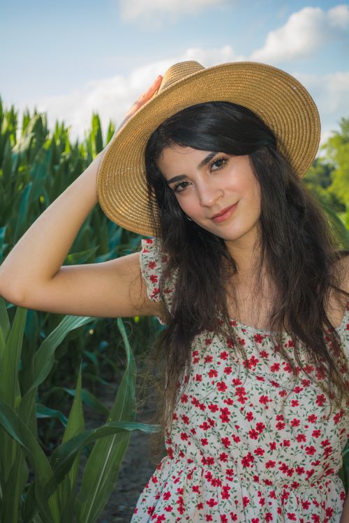 Free Smiling woman in a floral dress and straw hat poses in a sunny field. Stock Photo