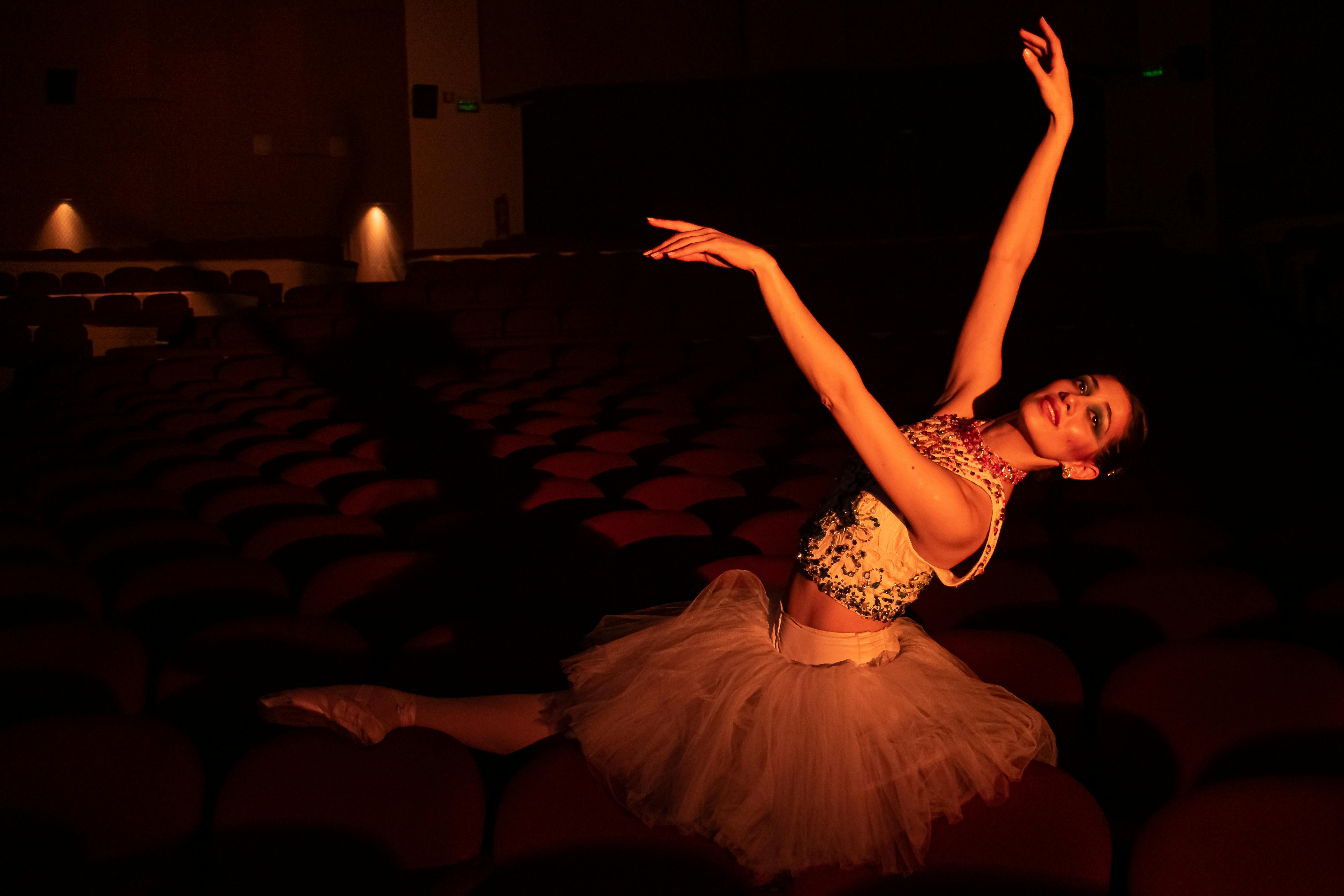 Free A graceful ballerina elegantly performing in an atmospheric theater setting. Stock Photo