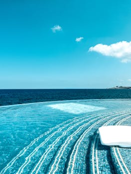 Tranquil infinity pool with stunning ocean view under a clear blue sky, perfect for relaxation.