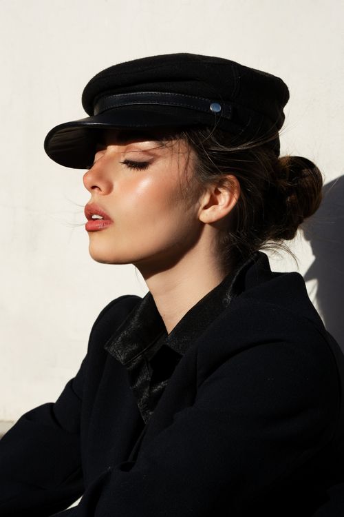 Free Stylish woman posing with closed eyes in sunlight, wearing a fashionable hat. Stock Photo