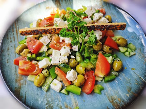 A vibrant salad with feta, olives, tomatoes, and peppers on a blue plate.