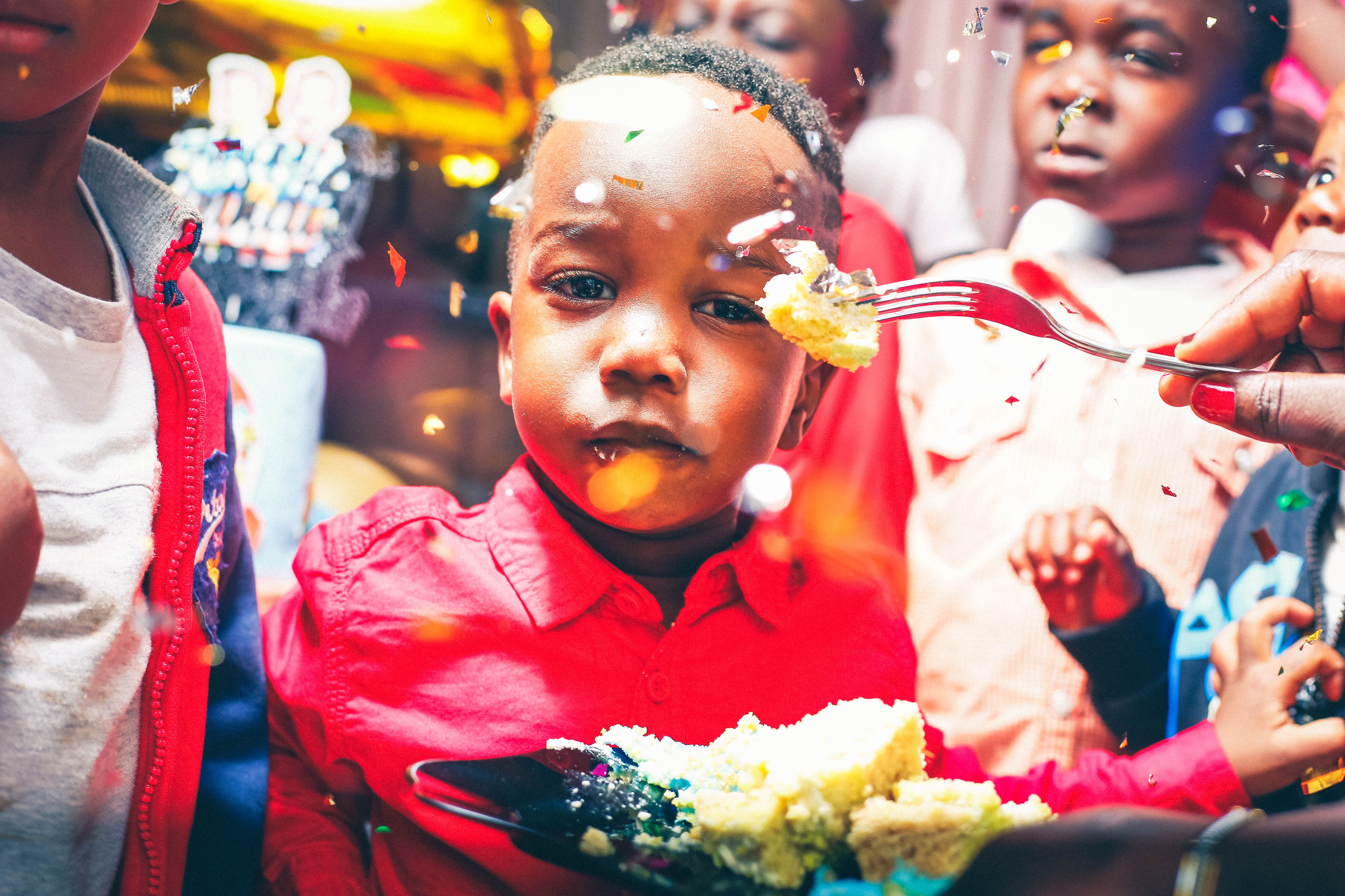 A joyful birthday party scene with children enjoying cake and confetti indoors.