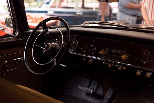 Close-up of a vintage car interior featuring a classic steering wheel and dashboard details.