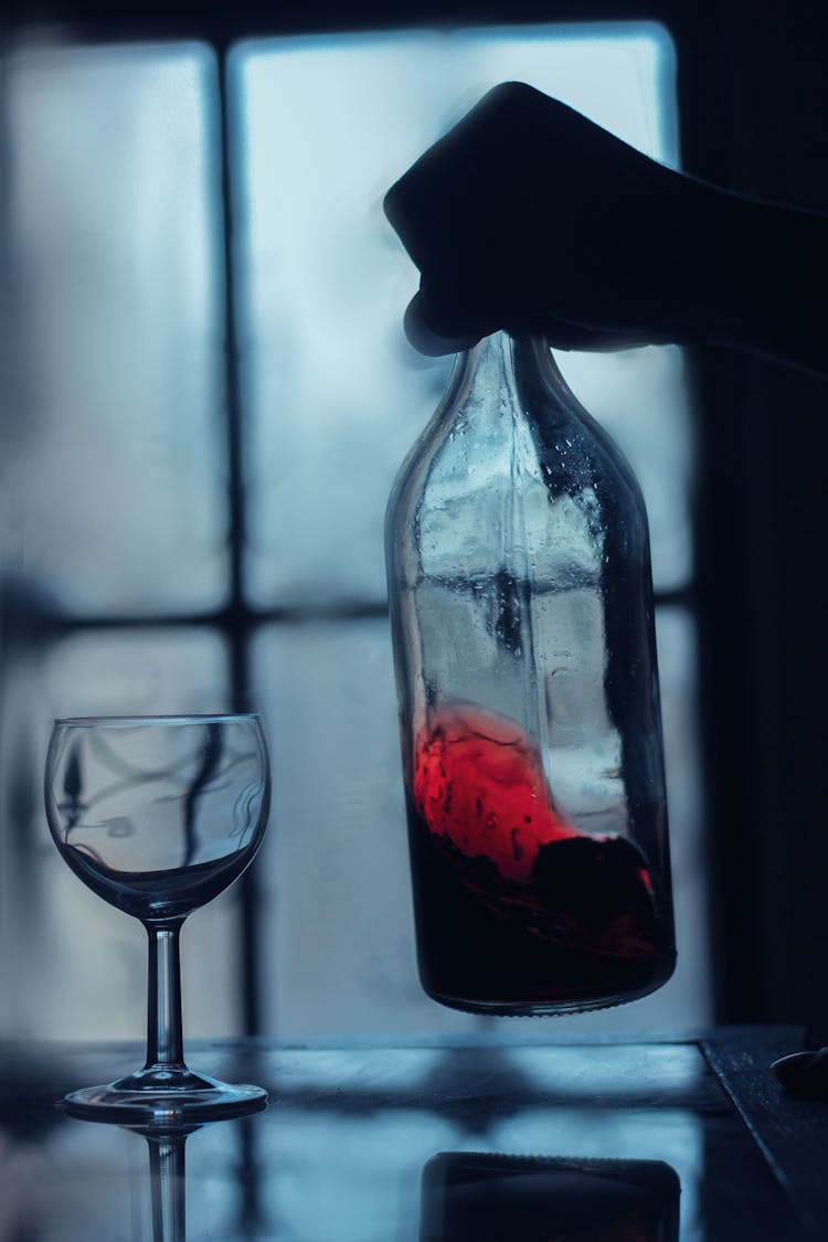 A Close-Up Shot Of A Person Swirling A Bottle Of Wine