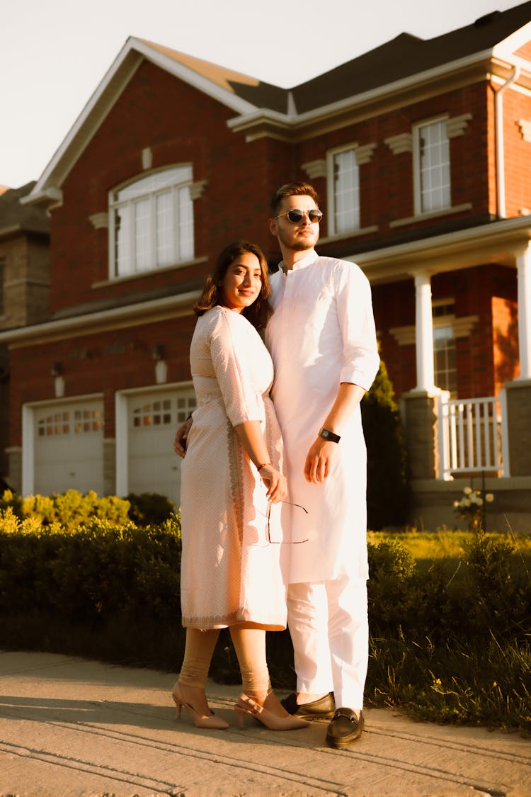 A Couple Standing Near On The Brown Concrete House