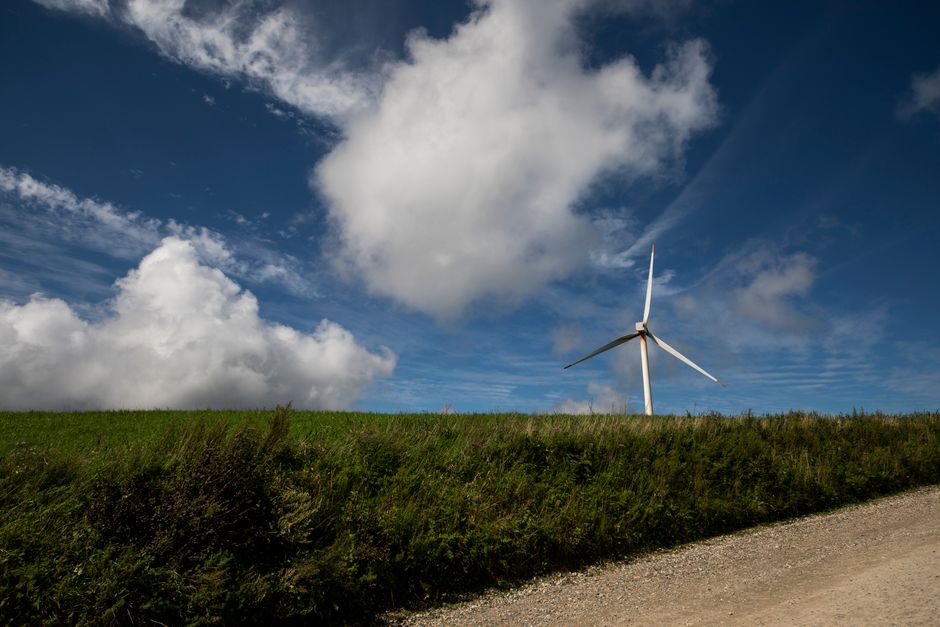 Wind turbine standing tall in Gangneung countryside under bright blue sky with white clouds.