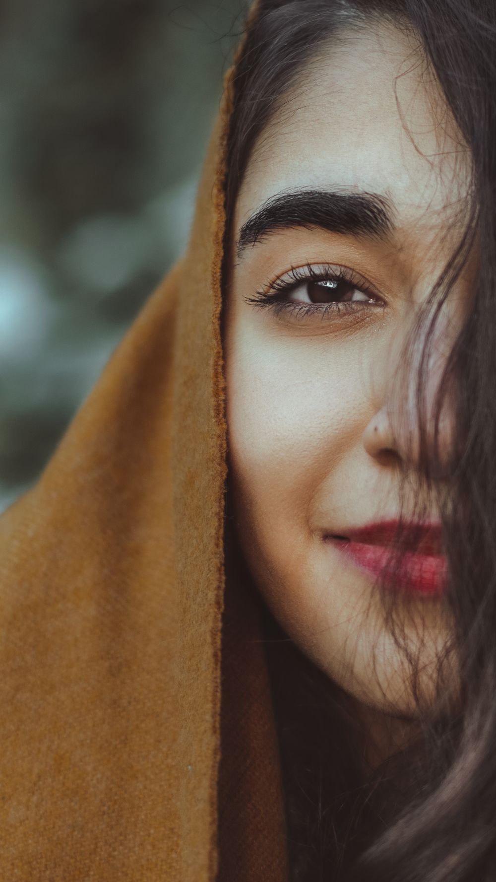 Close-up of a smiling woman wrapped in an ochre shawl