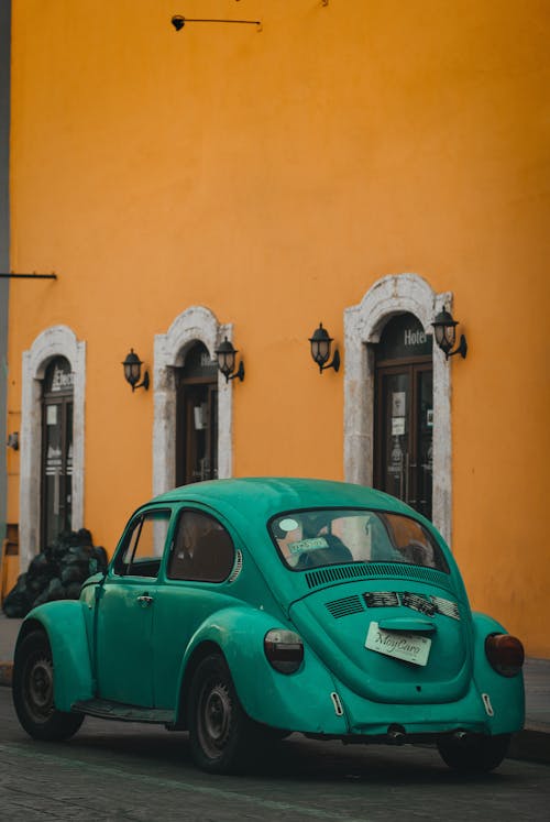Green Volkswagen Beetle Parked Beside Yellow Painted Building