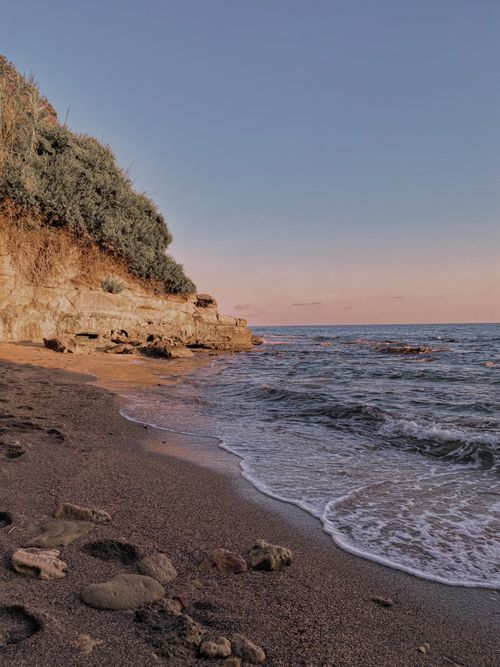 Free Calm sandy beach in Antalya, Turkey with gentle waves and cliffs at sunset. Stock Photo