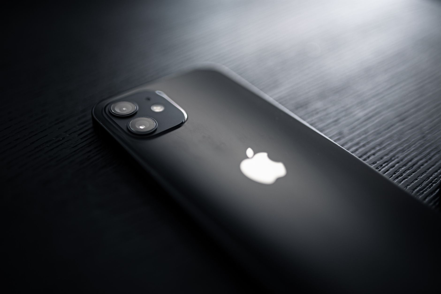Detailed close-up image of a sleek black smartphone with dual cameras on a textured surface.