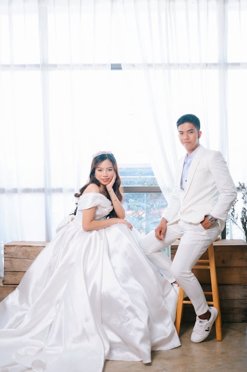 Free Man in White Suit Standing Beside Woman in White Wedding Dress Stock Photo