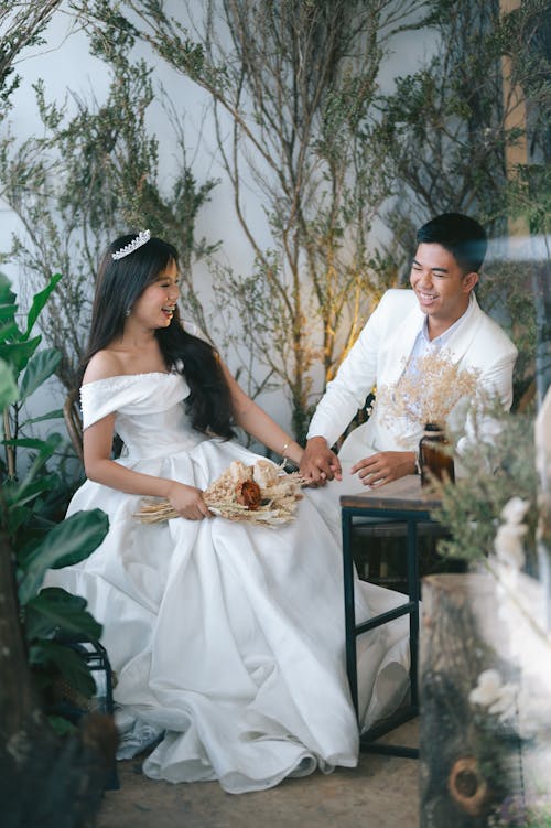 Man and Woman in Wedding Dress Sitting on Chair