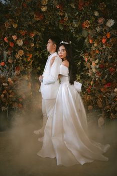 Bride and groom embracing in an elegant floral setting, exuding romance and love.