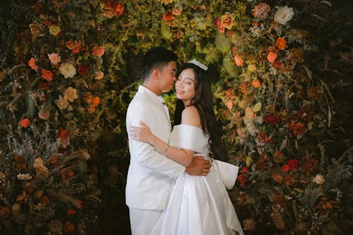 Man and Woman Standing Beside Red Flowers