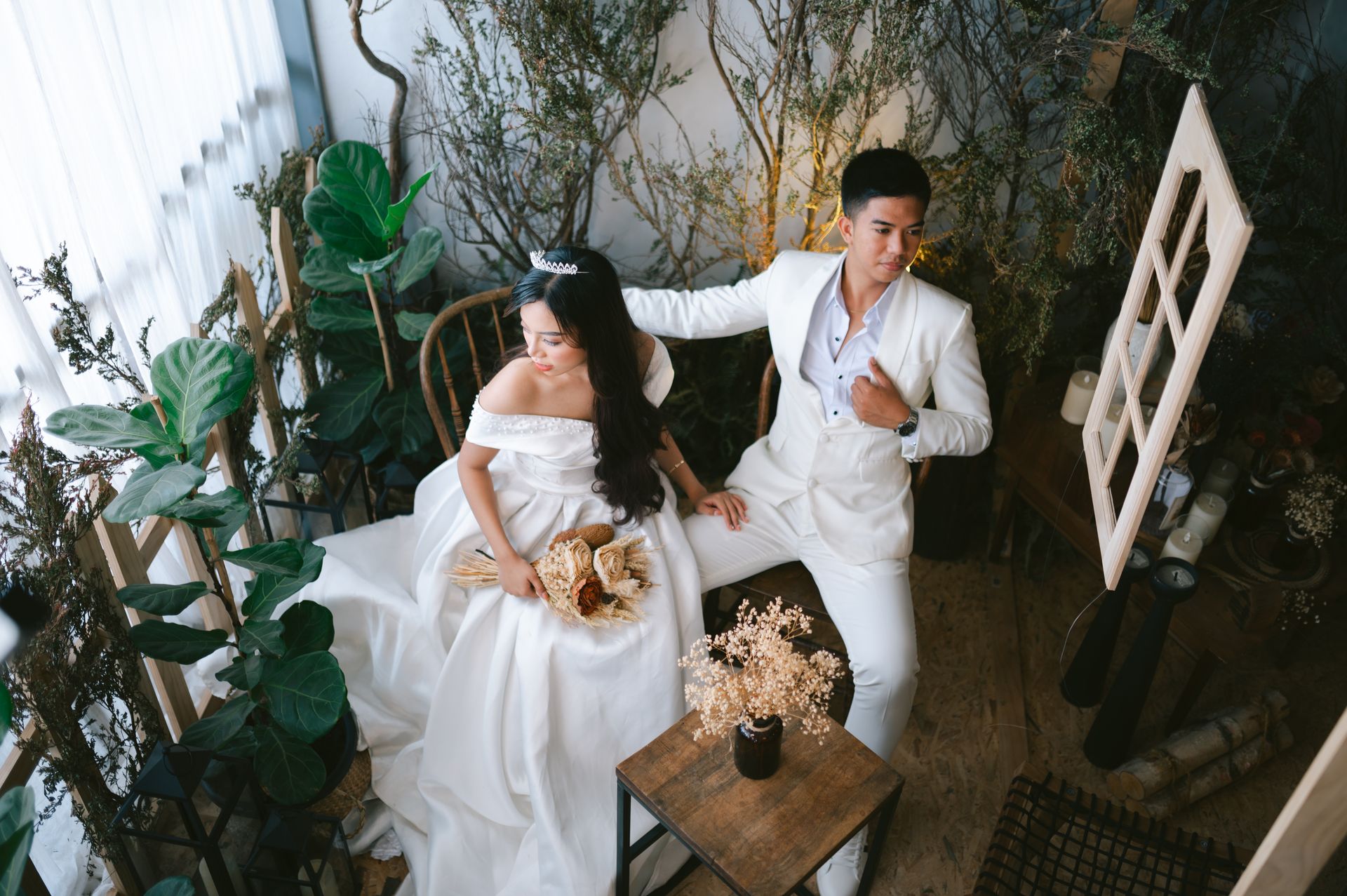 Woman and Man in Wedding Dress and Suit Sitting with Bouquet