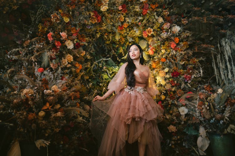 Woman In Tulle Gown Standing In Front Of Wall Of Flowers