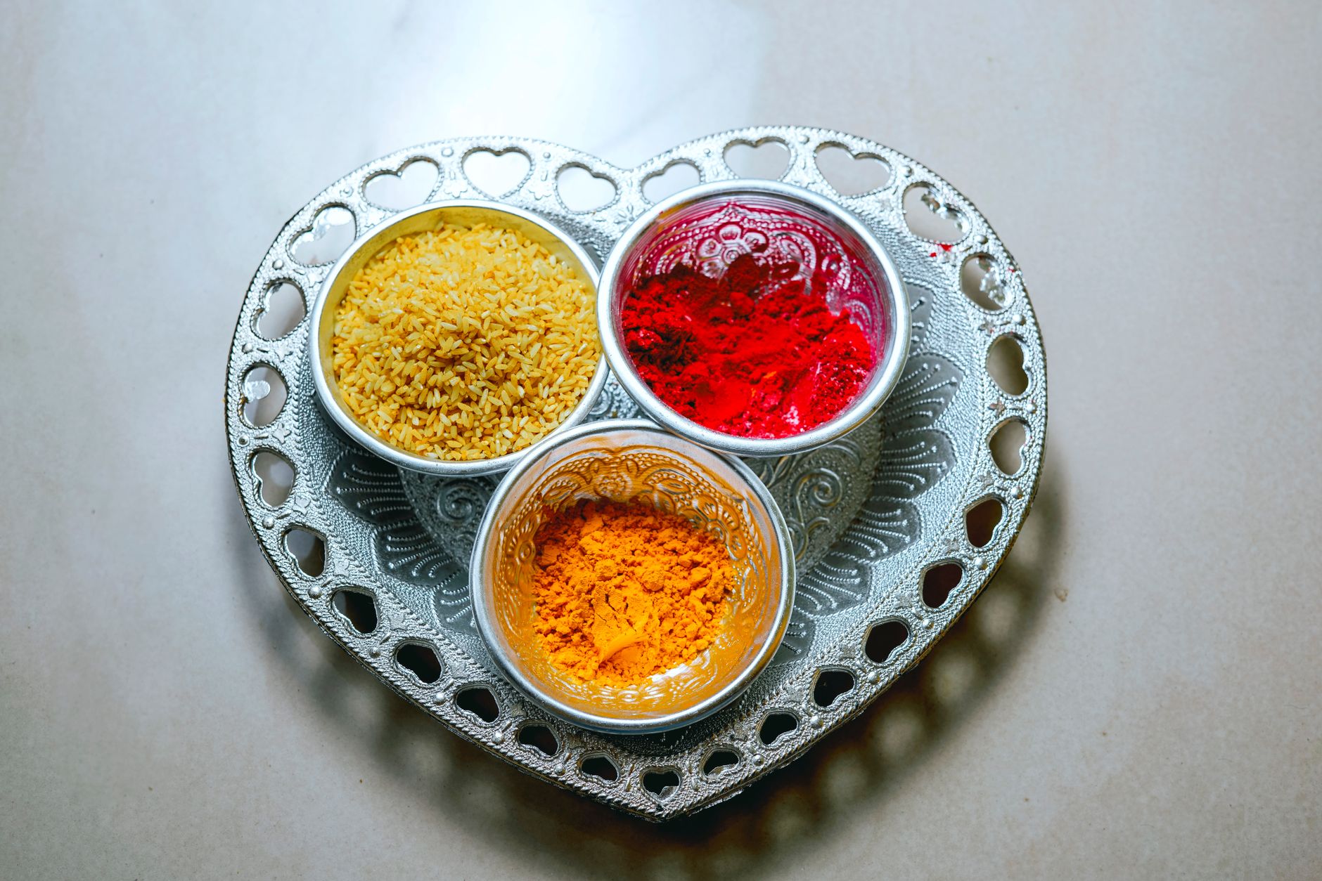 Top view of vibrant spices and rice on a heart-shaped tray, showcasing Indian flavors.