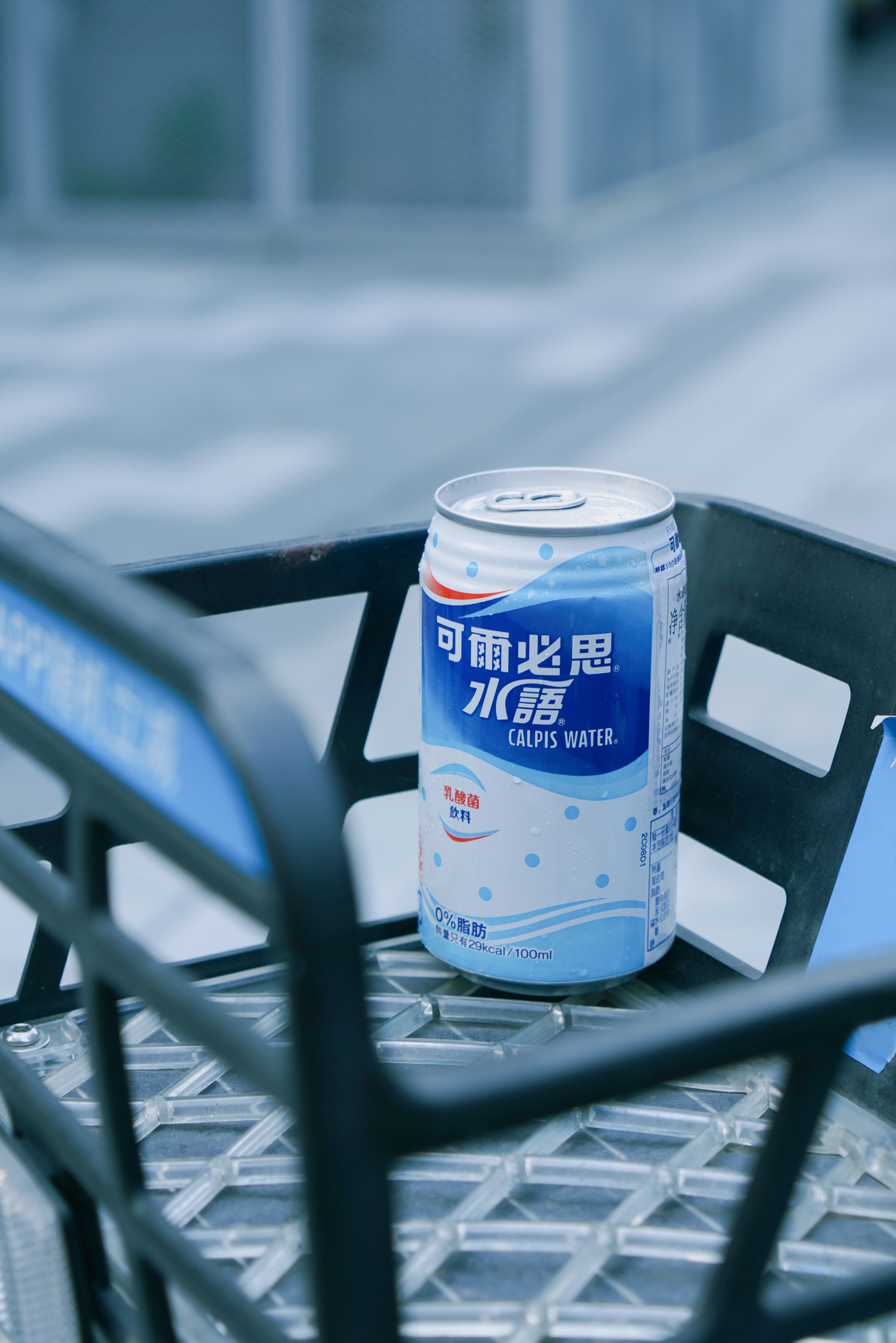 A can of Calpis Water is placed in a metal basket outdoors, showcasing its branding.
