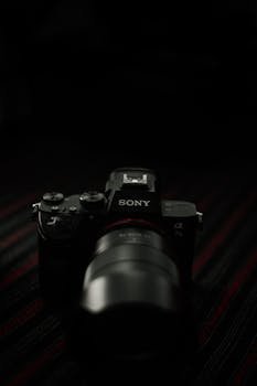 Close-up of a professional DSLR camera in low light setting, emphasizing lens detail.
