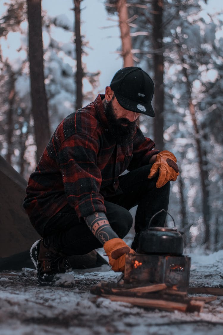 Male Camper Starting A Campfire In Winter