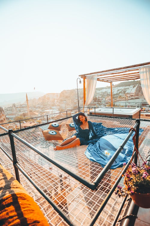 Free Woman Relaxing on a Rooftop with the View on a City in the Background  Stock Photo