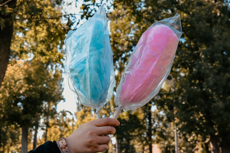 Person Holding Cotton Candies Wrapped In Plastic