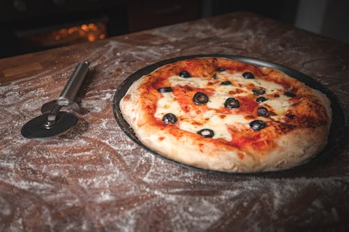 Pizza and Pizza Cutter on Table