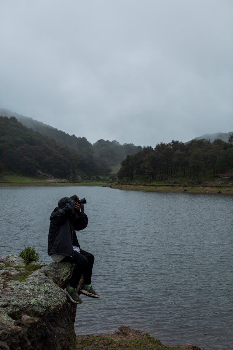 Man Sitting On A Rock Holding A Camera