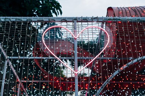 Free Neon heart sculpture with festive lights on a fence in urban Bangkok, Thailand. Stock Photo