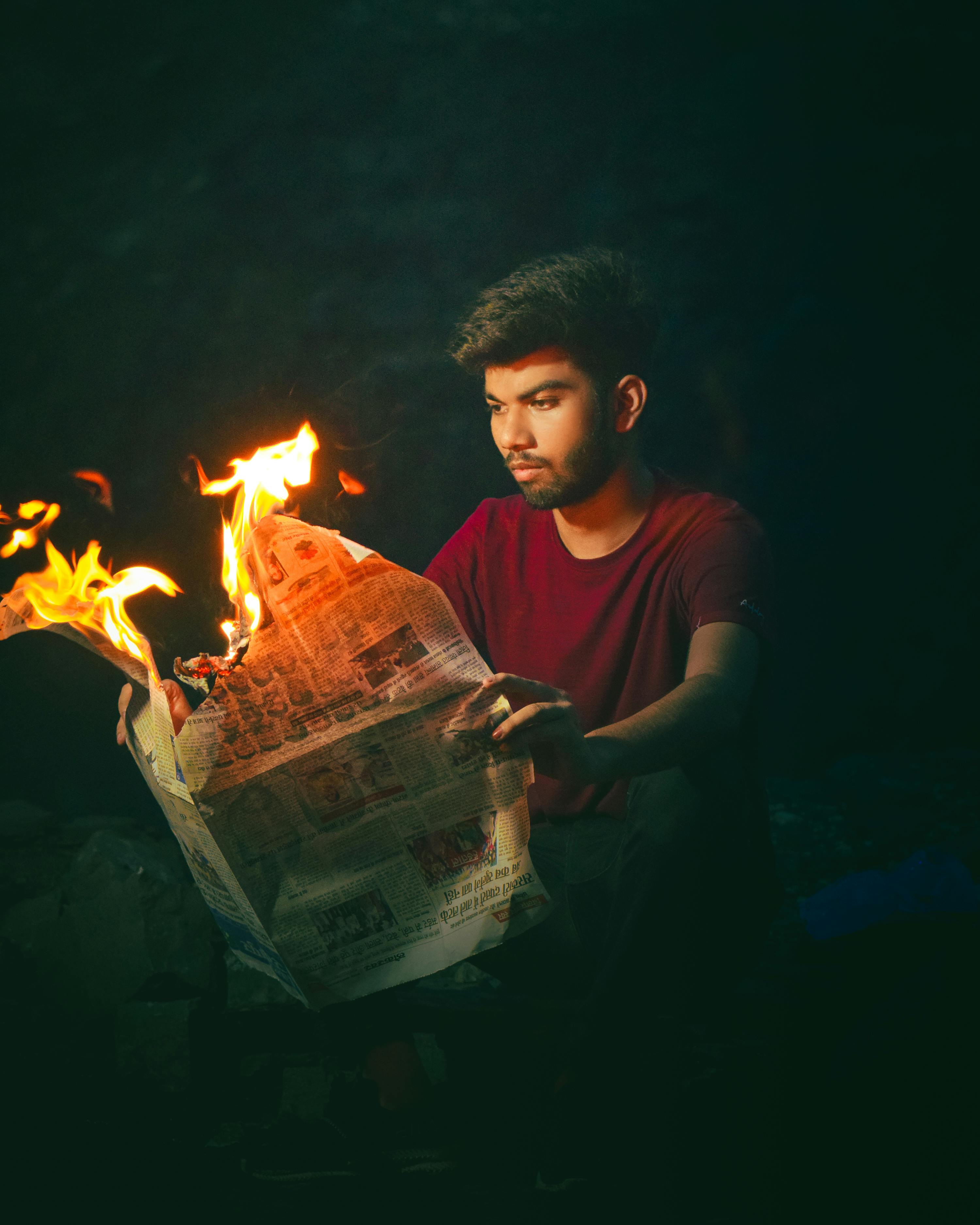 A Man Reading a Burning Newspaper on a Beach · Free Stock Photo