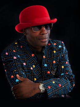 Portrait of a man in a red hat and retro gaming pattern jacket, exuding confidence.