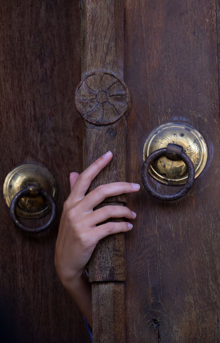 A Person Holding Brown Wooden Door