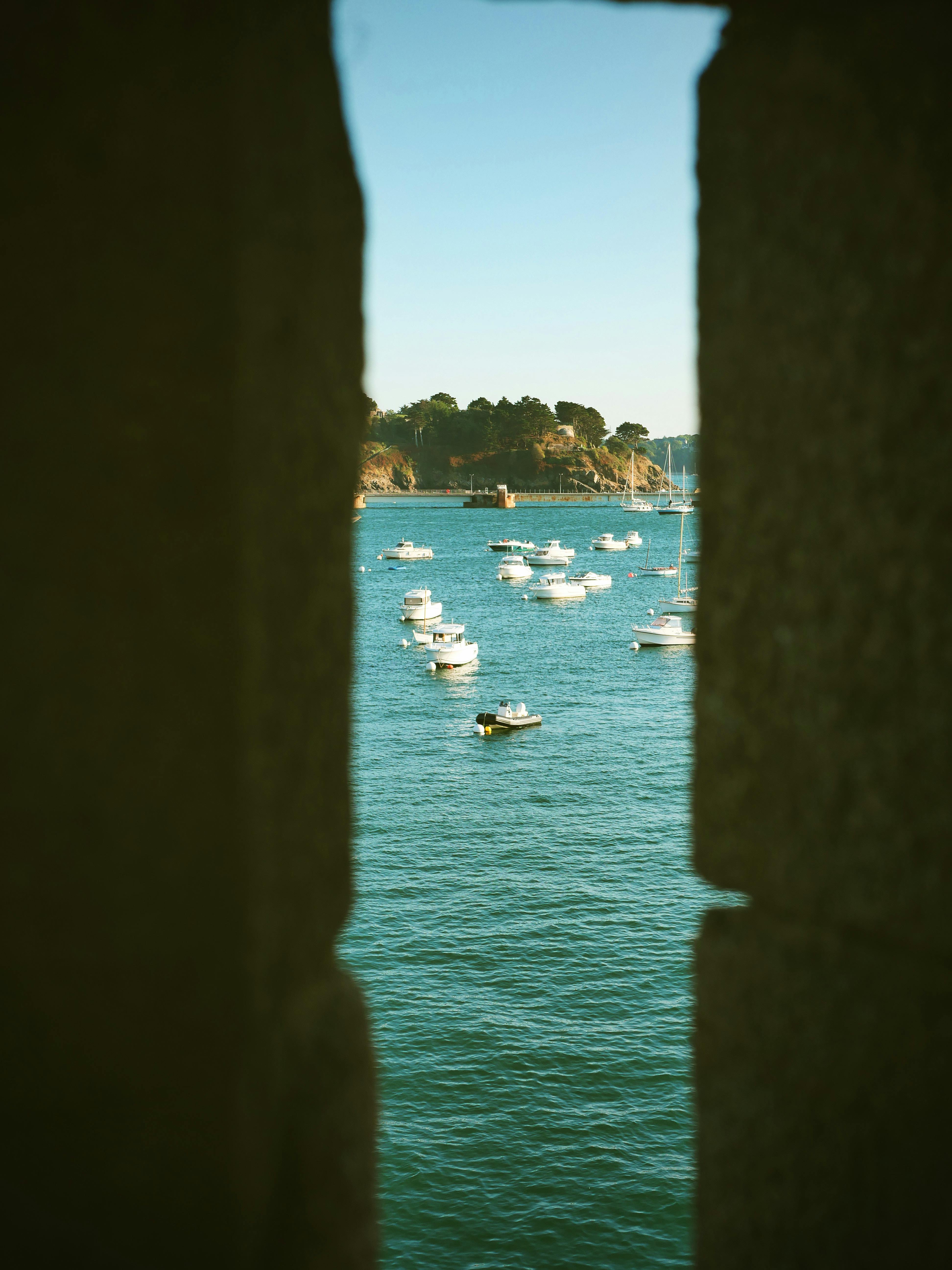 Charming view of boats on a calm Brittany seashore, captured through an old stone window frame.
