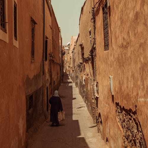 Woman Walking in a Narrow Alley between Traditional Buildings