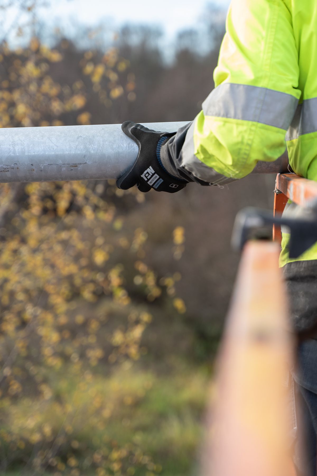 Arbeiter mit Rohrstück und Schutzkleidung bei einer Leitungsarbeit