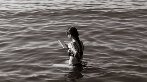 Free Woman Standing in Water and Reading a Book  Stock Photo