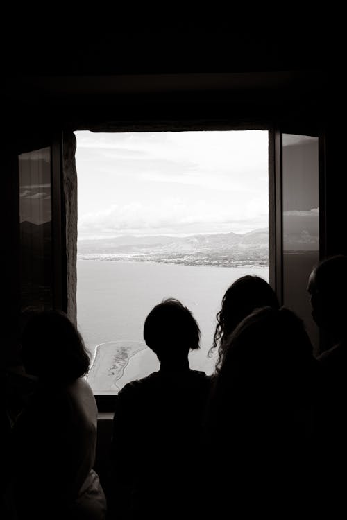 Silhouette of People standing in front of a Window Looking at the Sea