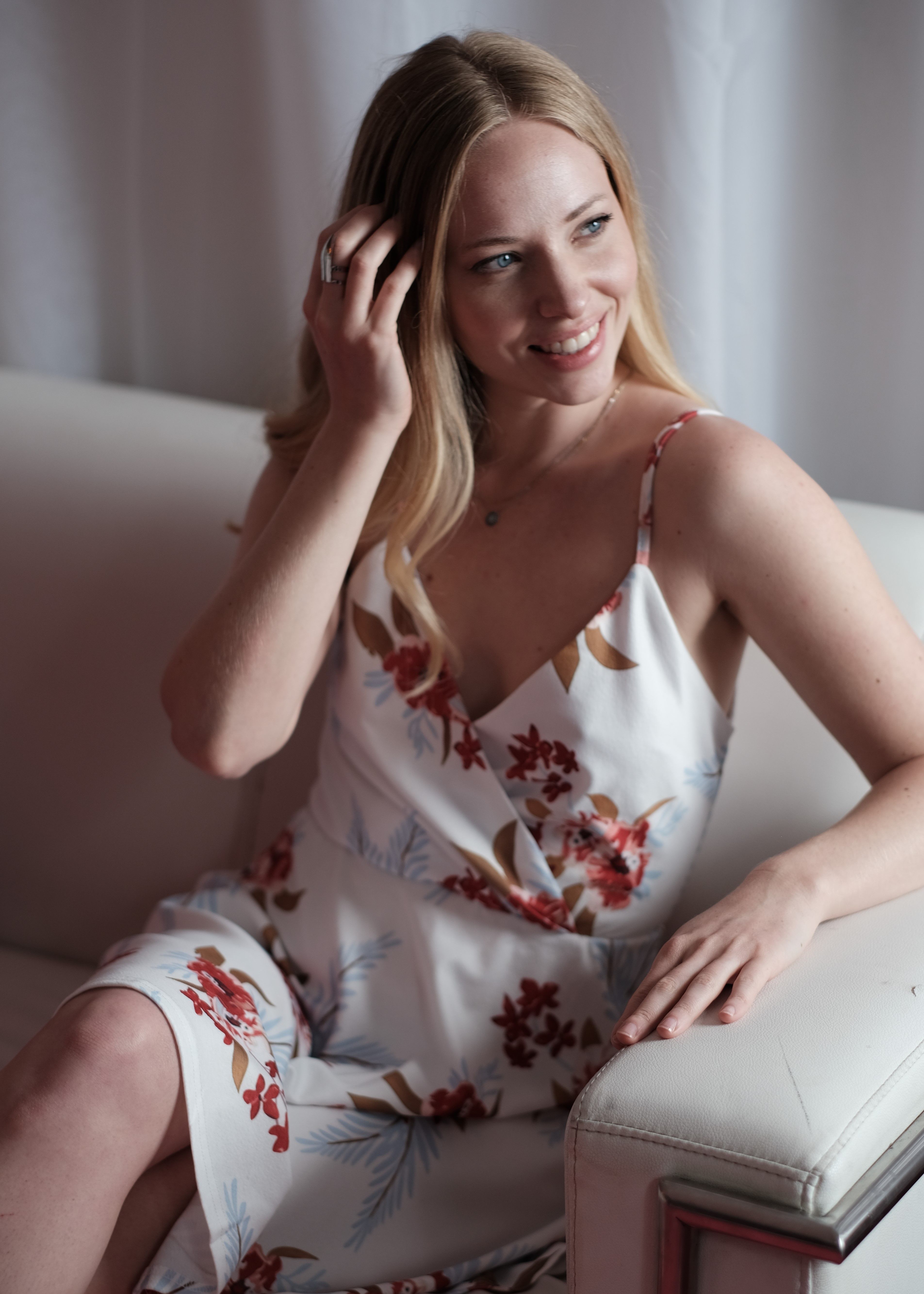 Smiling Woman in a Floral Dress Sitting on a Couch · Free Stock Photo