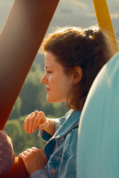 Free Profile of a young woman in a denim jacket enjoying a peaceful hot air balloon ride. Stock Photo