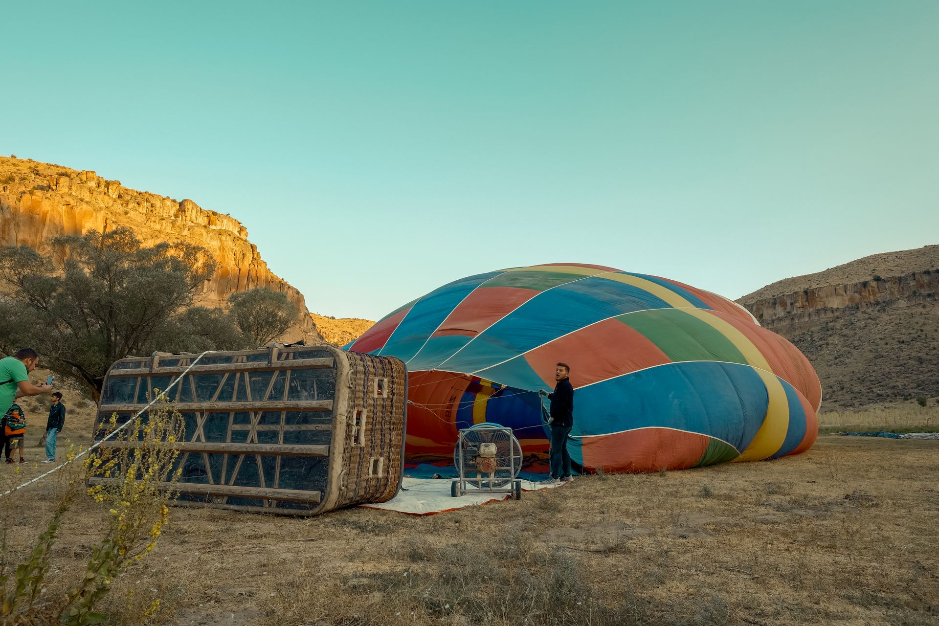 A vibrant hot air balloon being prepared for launch in a scenic outdoor landscape.