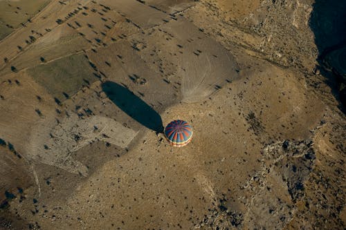 Aerial View of a Blue and Red Hot Air Balloon on Brown Sand
